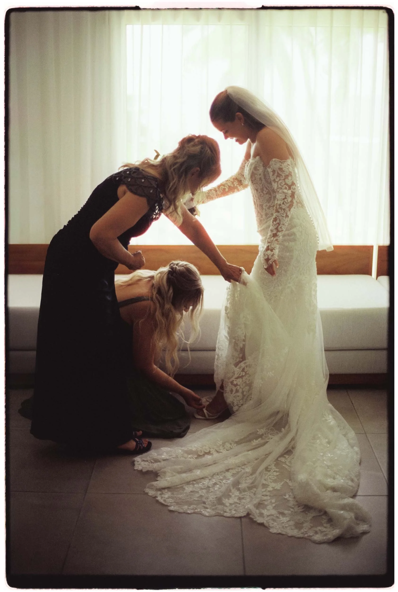 35mm film of the bride getting help from her sister and mom to get fully dress.