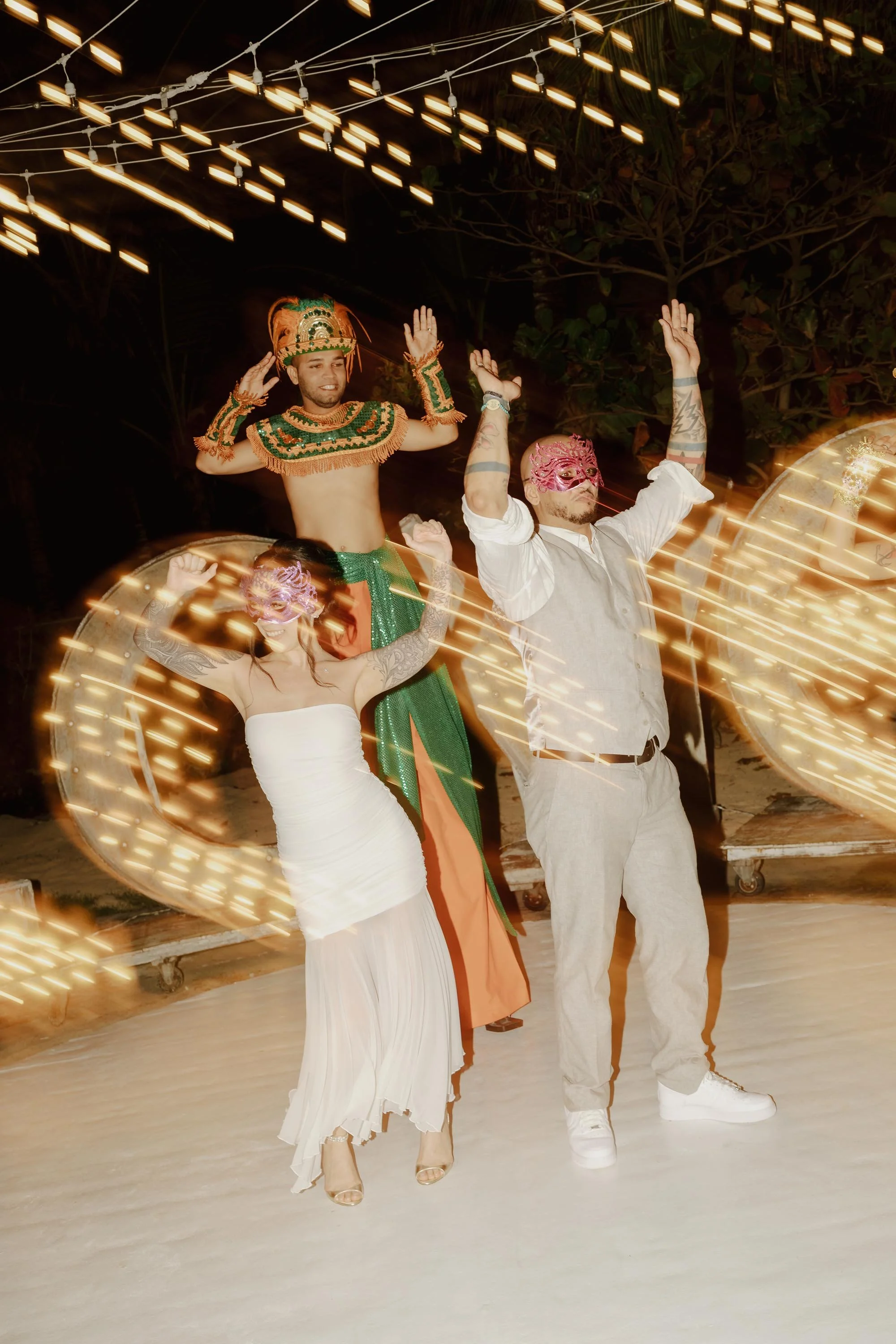 Motion blur photo of a bride and groom dancing in masks with a Dominican Carnival stilt walker during the Hora Loca at their Kukua Beach Club wedding in Bavaro, Punta Cana.
