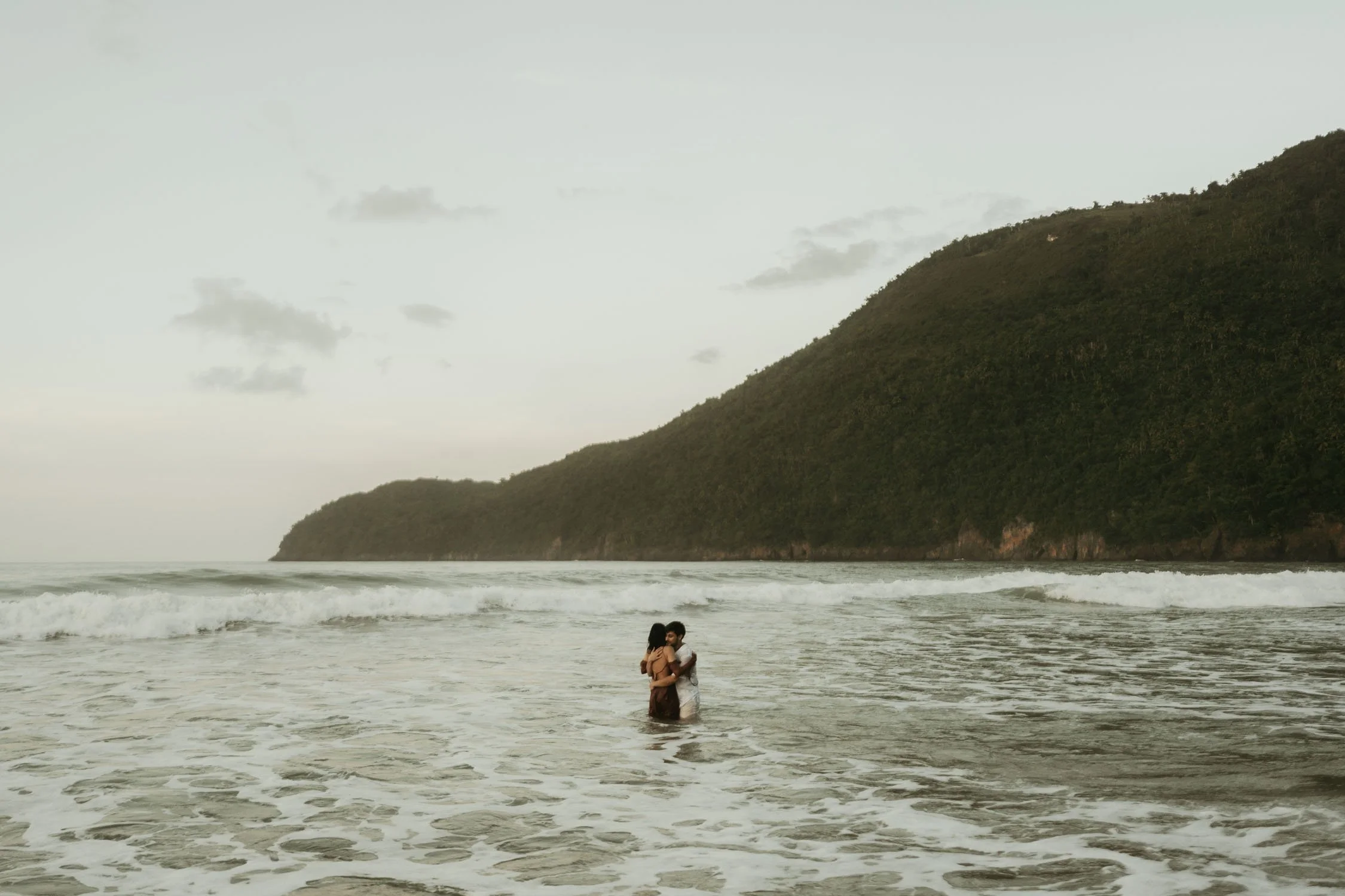 couple huging each other after running towards the beach in an engagement photoshoot in samana el valle dominican republic