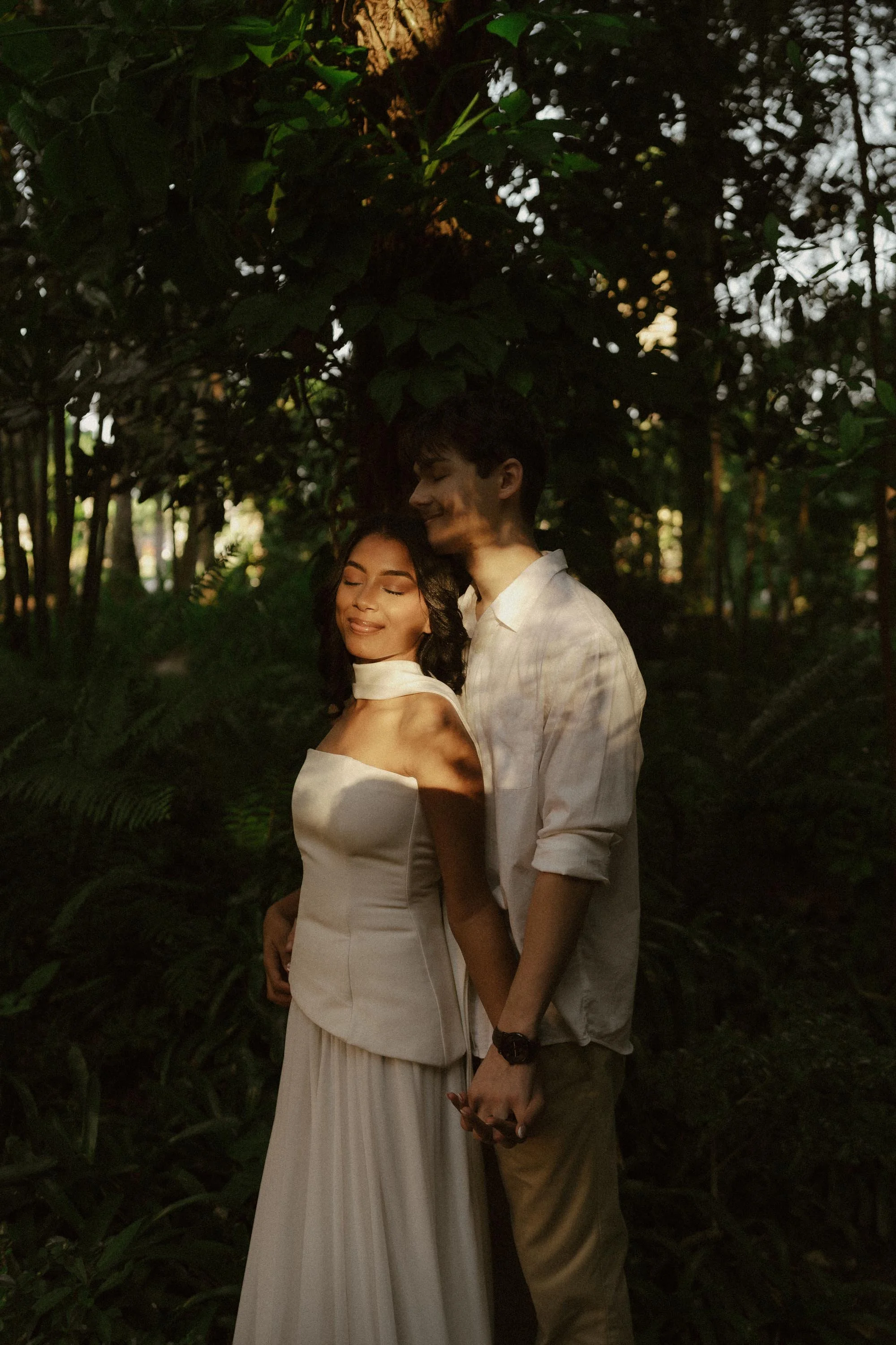 Couple sharing a quiet moment surrounded by lush greenery and filtered morning light at the Botanical Garden.