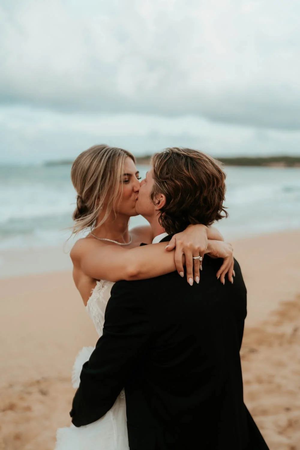 bride and groom kissing at the beach