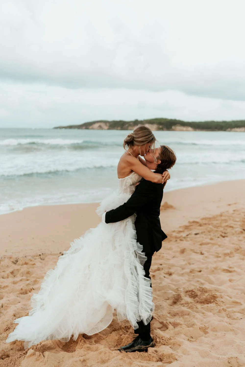 bride and groom kissing at the beach