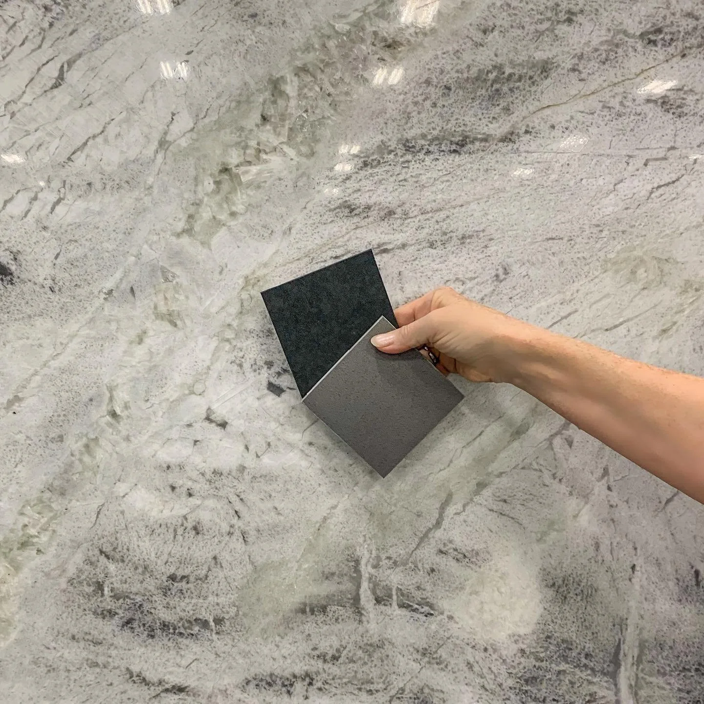 Our Designer Janice Hanks contemplating which solid surface to use in tandem with this spectacular slab of Palladium White quartzite from @agmgranite. A stone this beautiful is truly a work of art.  This kitchen island becomes a painting - the perime