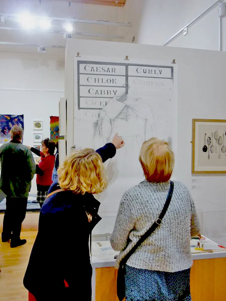 Visitors to the exhibition looking at my drawing of a farmers smock.