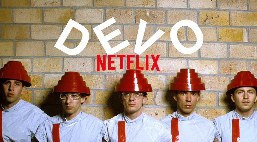 Photo of Devo members standing against a brick wall.