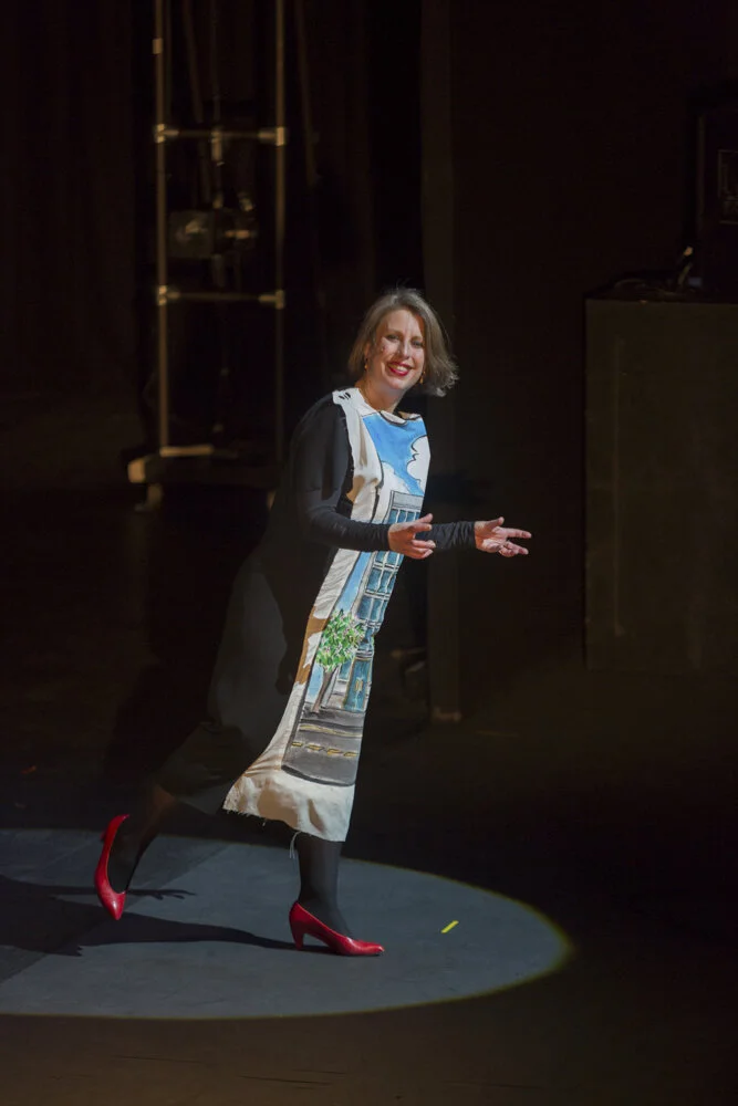 Hayley Newman smiling in pictorial dress and red shoes