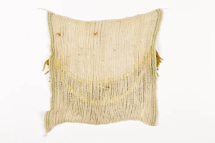 Underside of a used dishcloth with the suggestion of a face