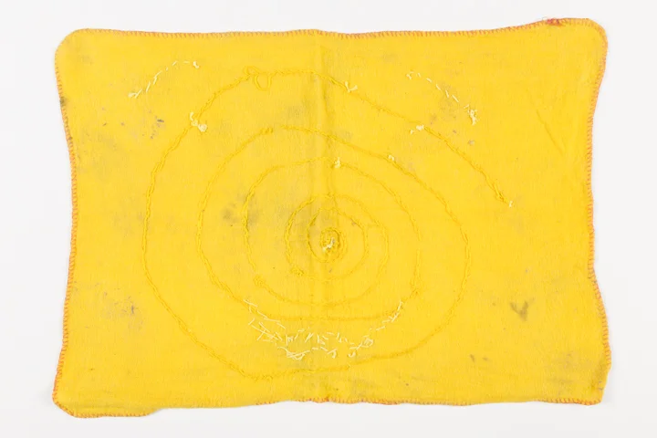 Reverse of a used yellow dishcloth with the suggestion of a face