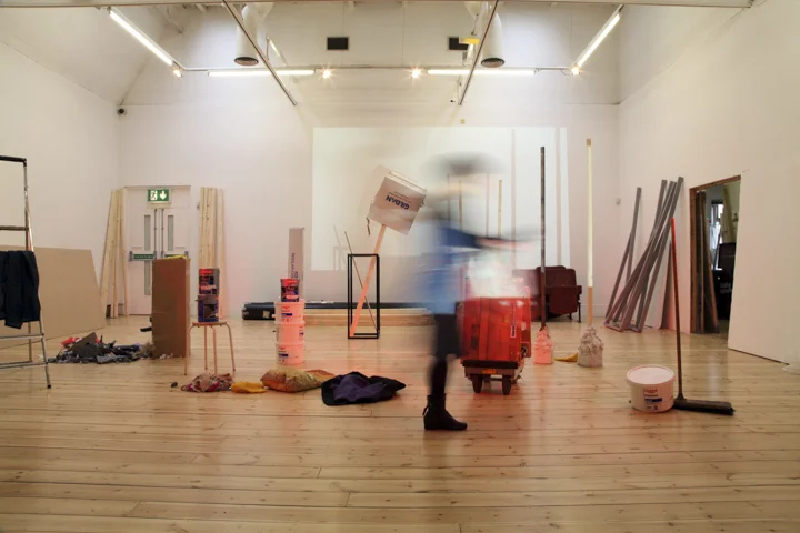 A range of everyday objects stand haphazardly in an art gallery