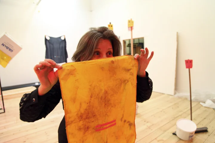 Hayley Newman holds a large dirty dishcloth by the corners which hides the lower half of her face
