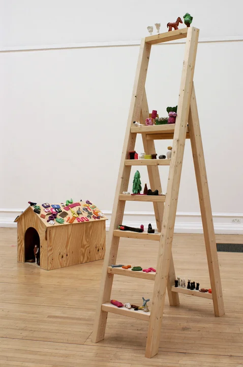 A wooden ladder and dog kennel on which are perched many small brightly coloured plasticine objects