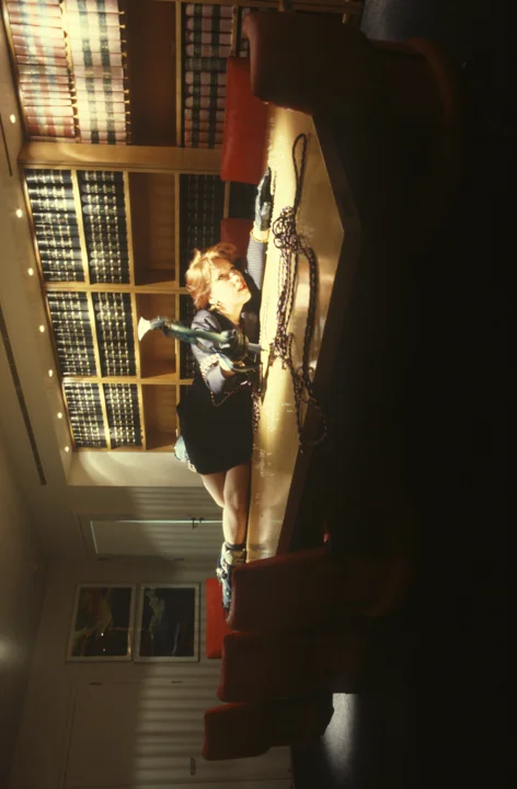 Hayley Newman, photographed vertically, lies on a boardroom table using mountaineering equipment