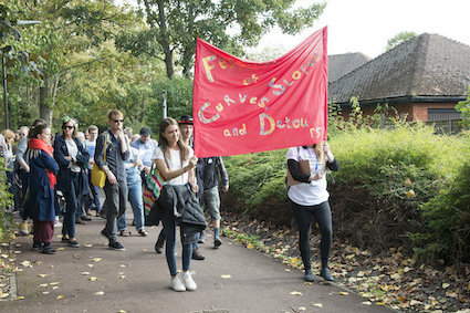 Two people in front of a walking group holding a red banner with the words - festival of curves, slopes and detours