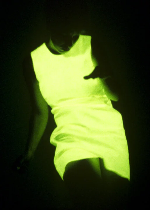 A sleeveless dress worn by Hayley Newman glowing green in darkness