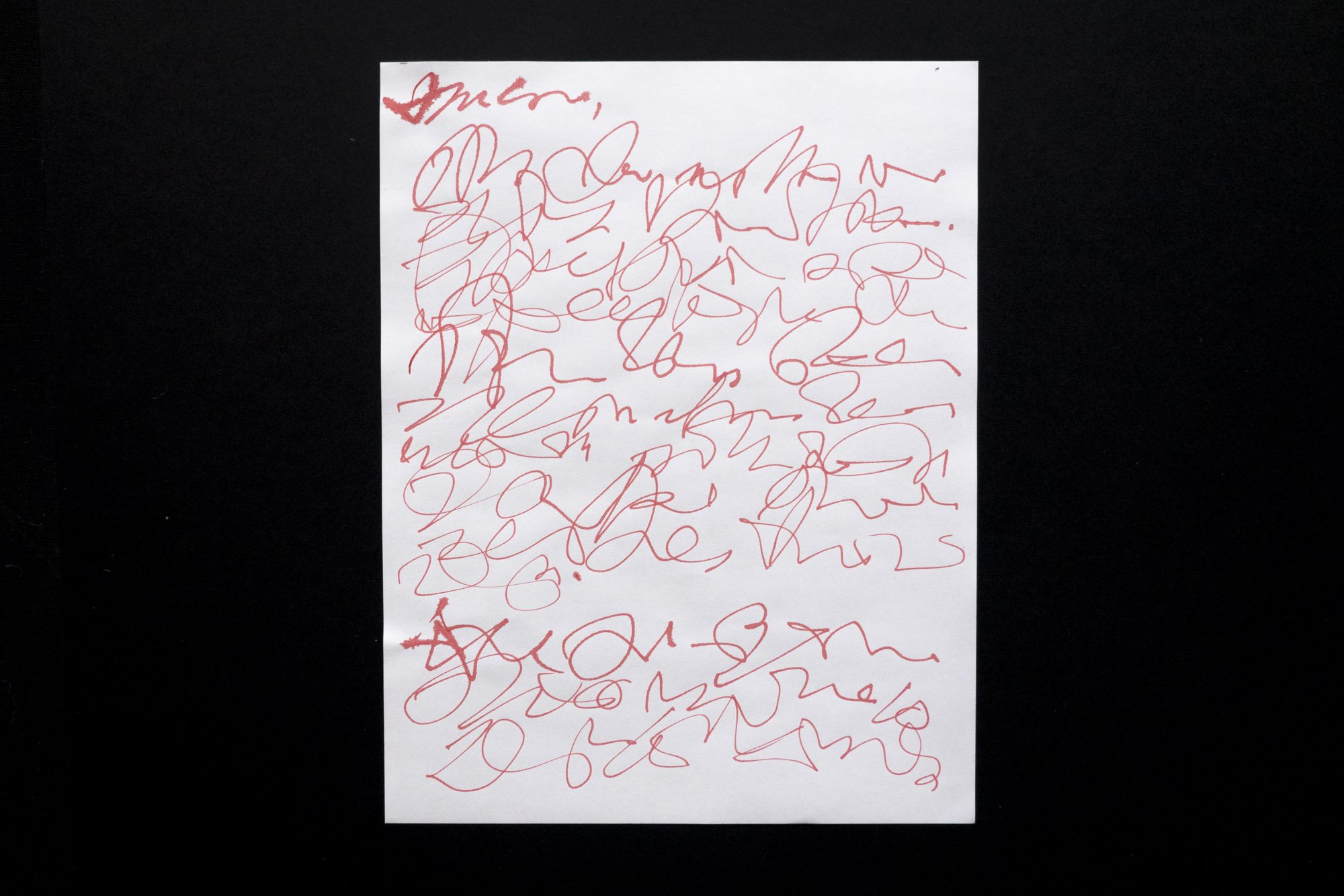 Red ink on paper that appears to be an agitated handwritten letter but that is completely illegible