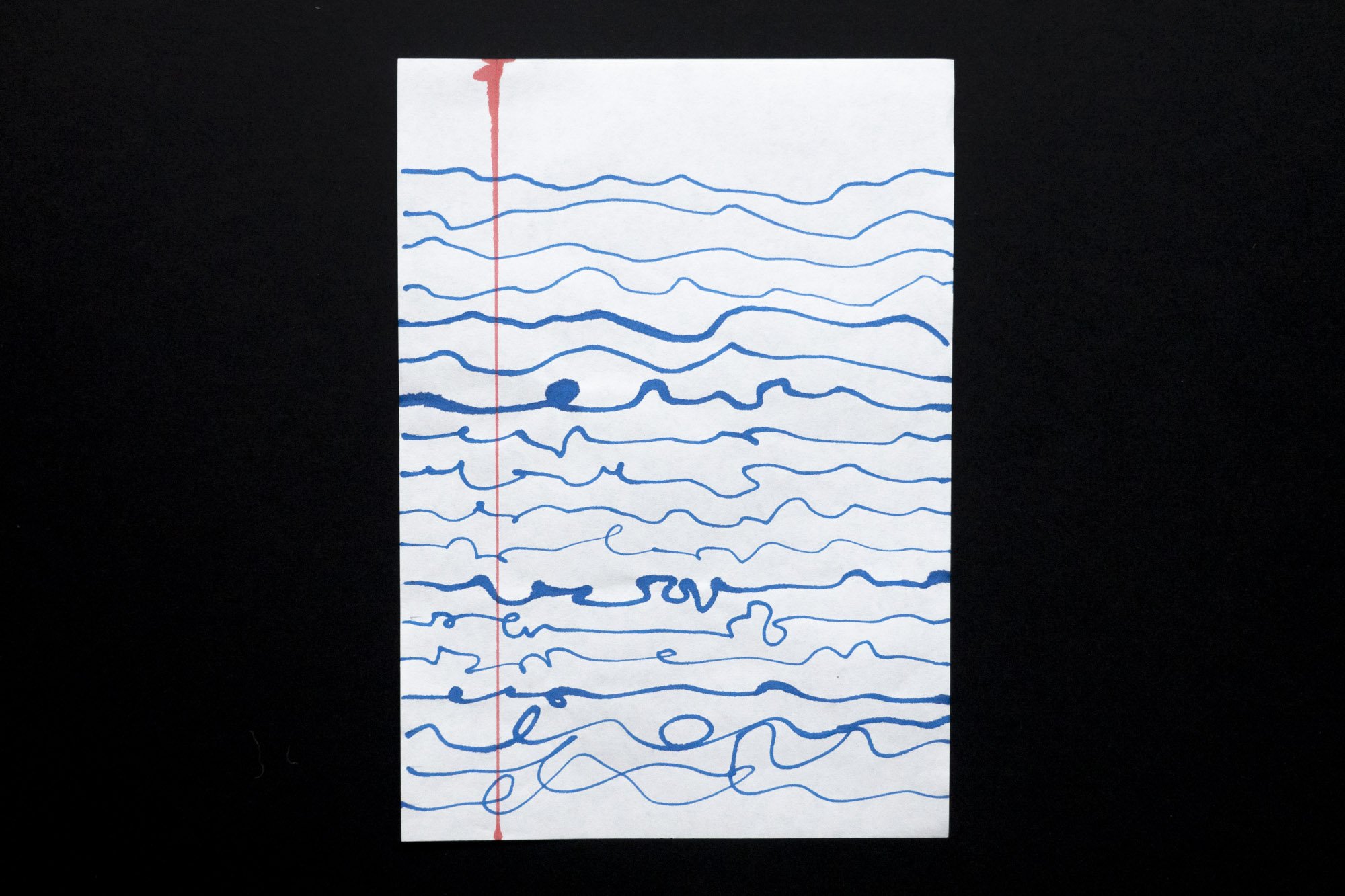 A white piece of paper on which irregular blue ink lines are drawn like handwriting or an electrocardiogram
