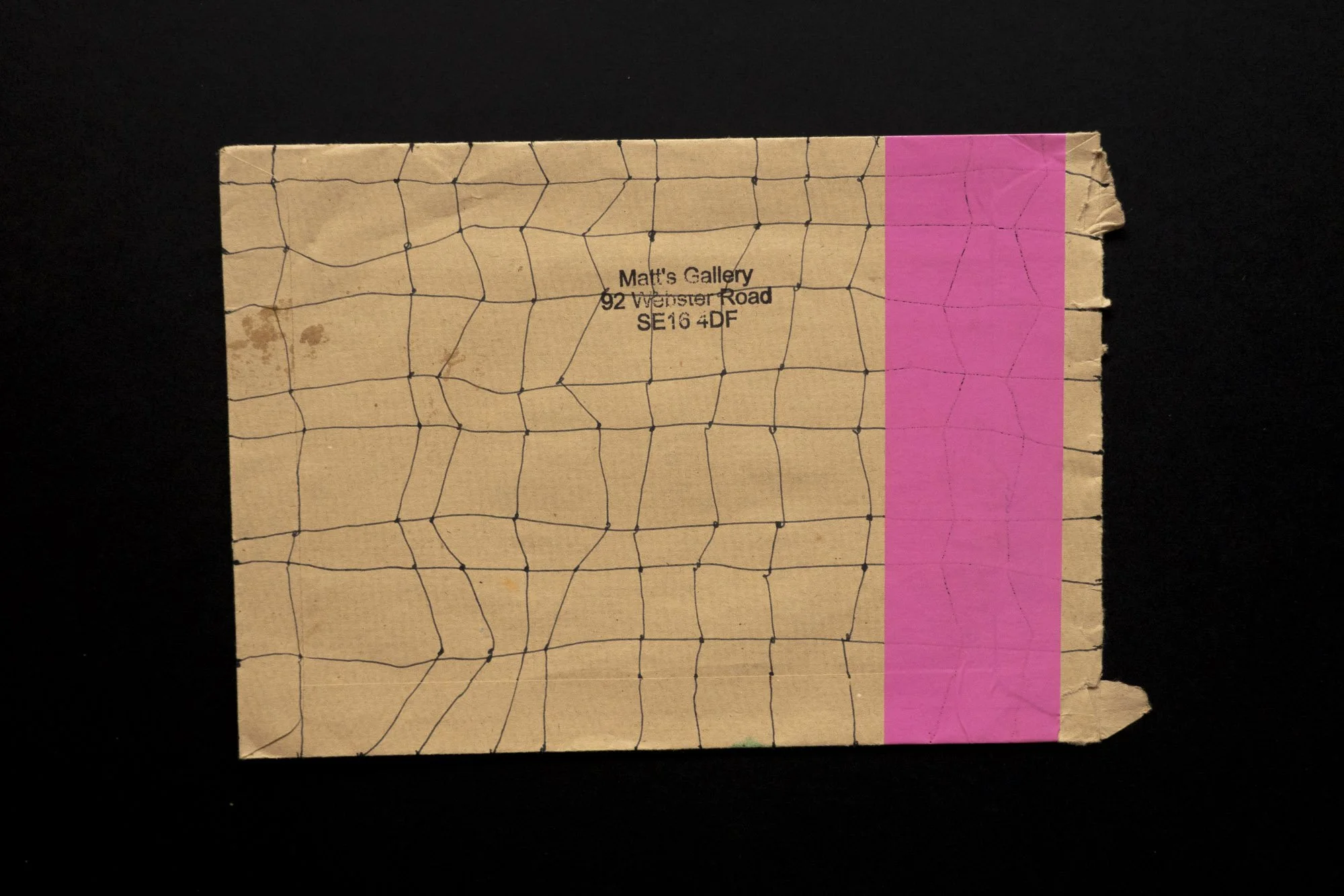 A brown envelope covered in a grid of hand-drawn lines rubber stamped - Matts Gallery and address