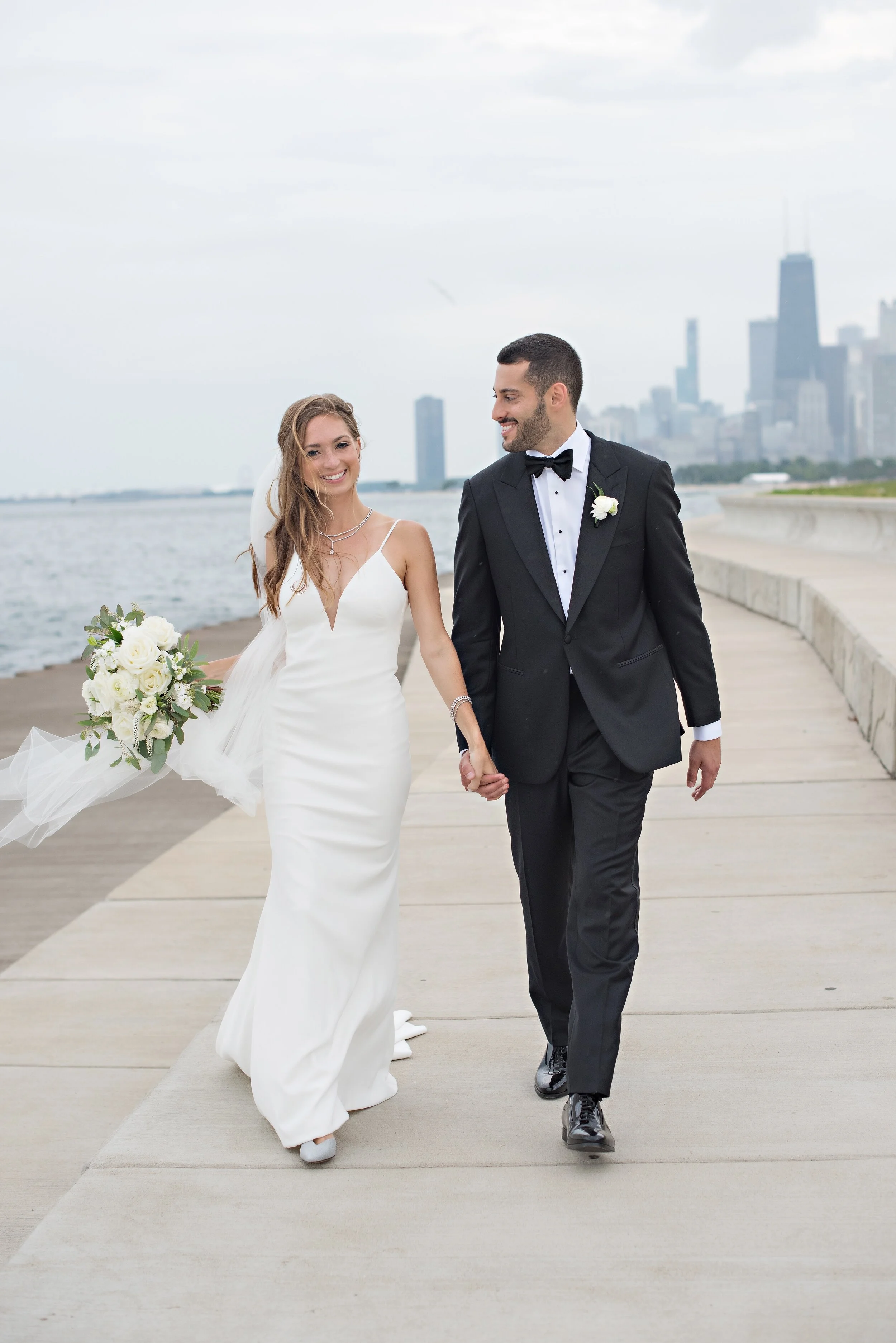 Bride and groom walking hand in hand along the Chicago lakefront