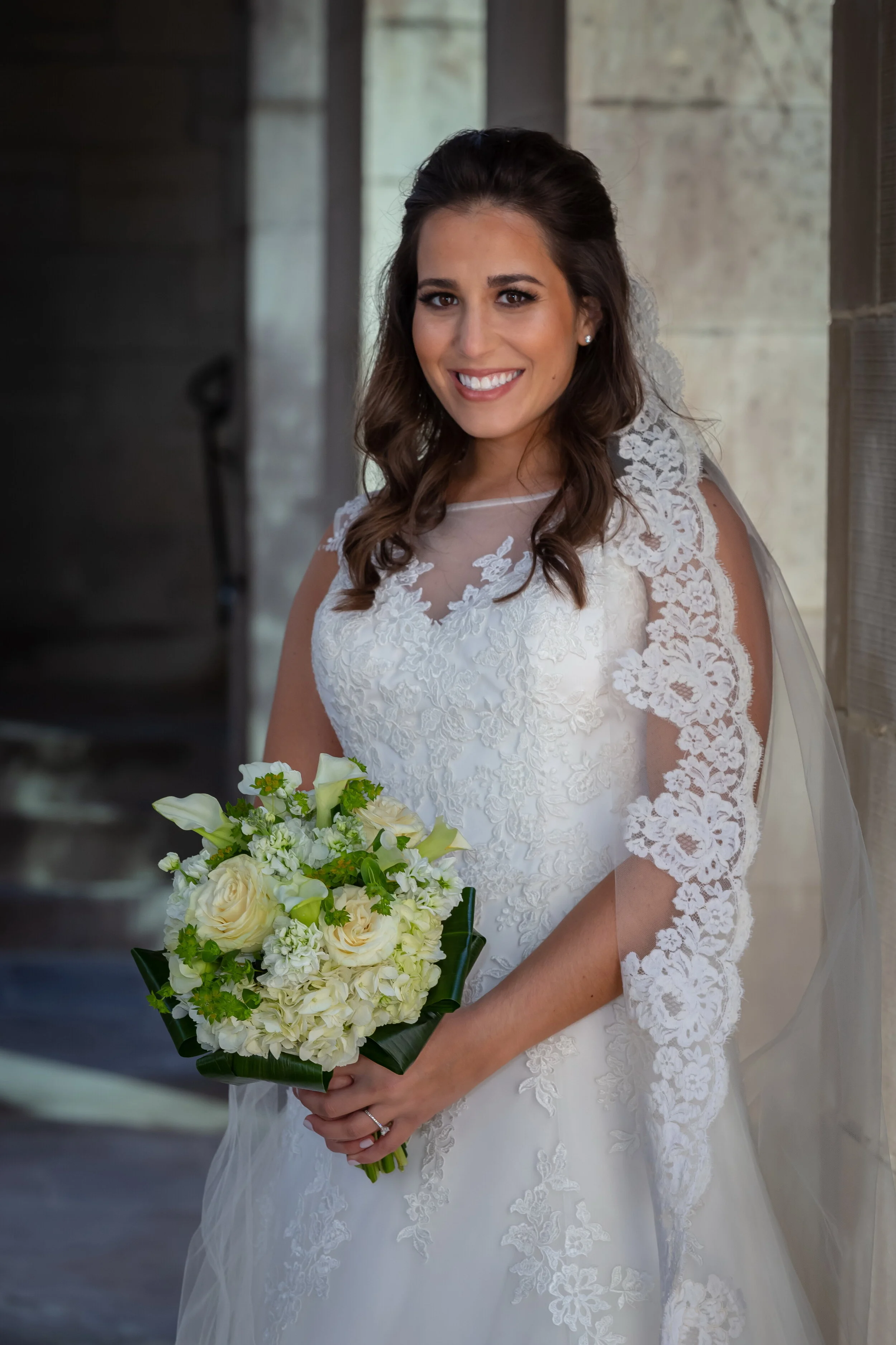 Bride in lace wedding dress holding white and green bouquet at Chicago venue