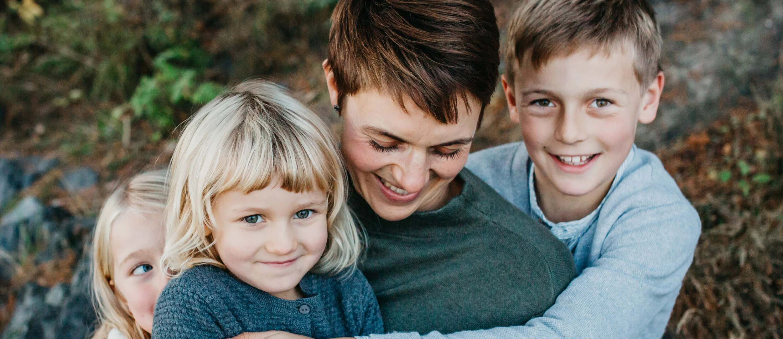 tre barn som kramar om mamman