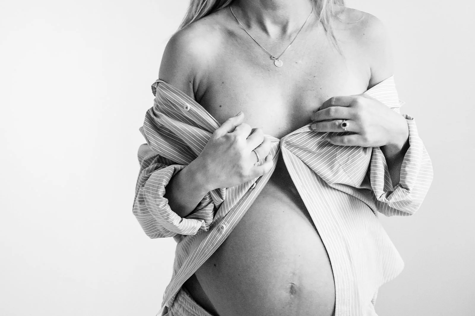 Gravid tjej med öppen skjorta på sig så att magen syns.