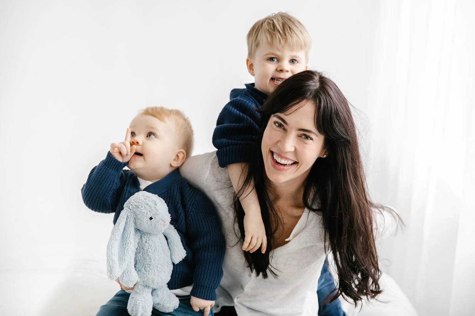 Mamma med två söner i toddler åldern. mamman har mörkt långt hår och barnen är blonda.
