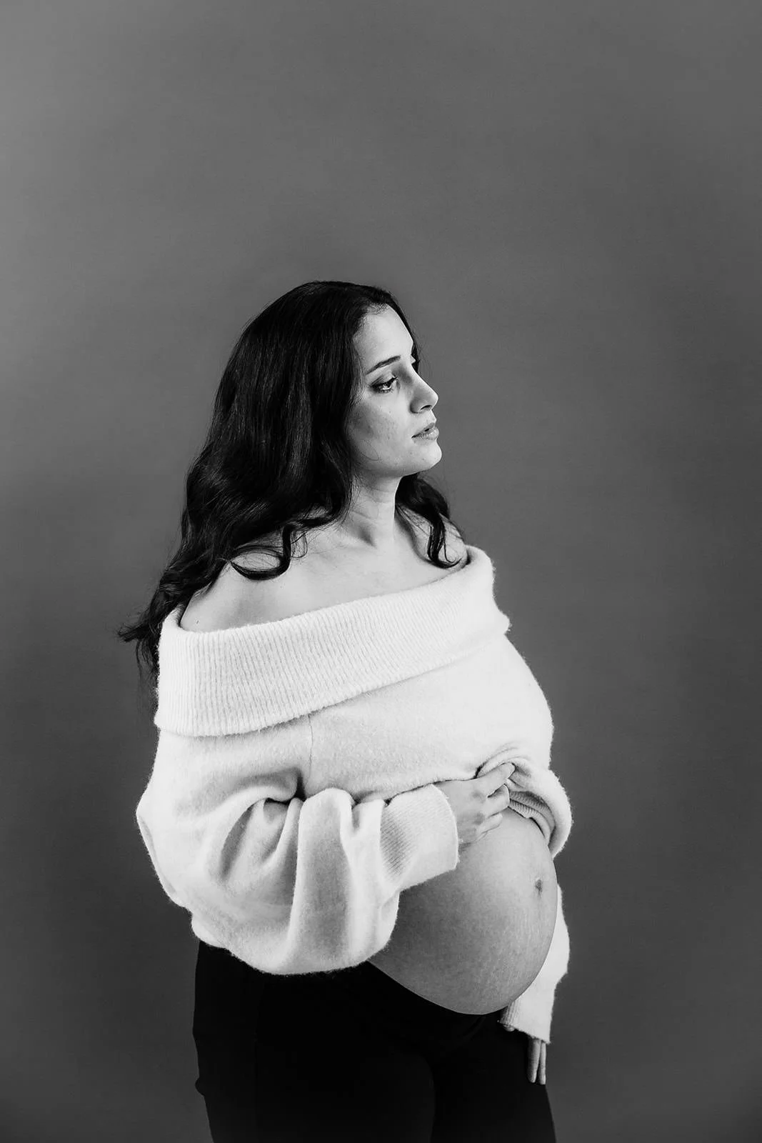 Kvinna som visar sin gravidmage i svartvitt.