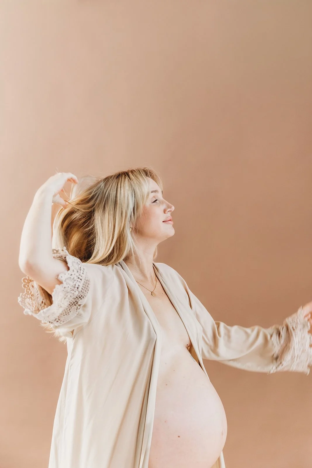 Gravid kvinna med bar mage som dansar och drar handen genom håret.