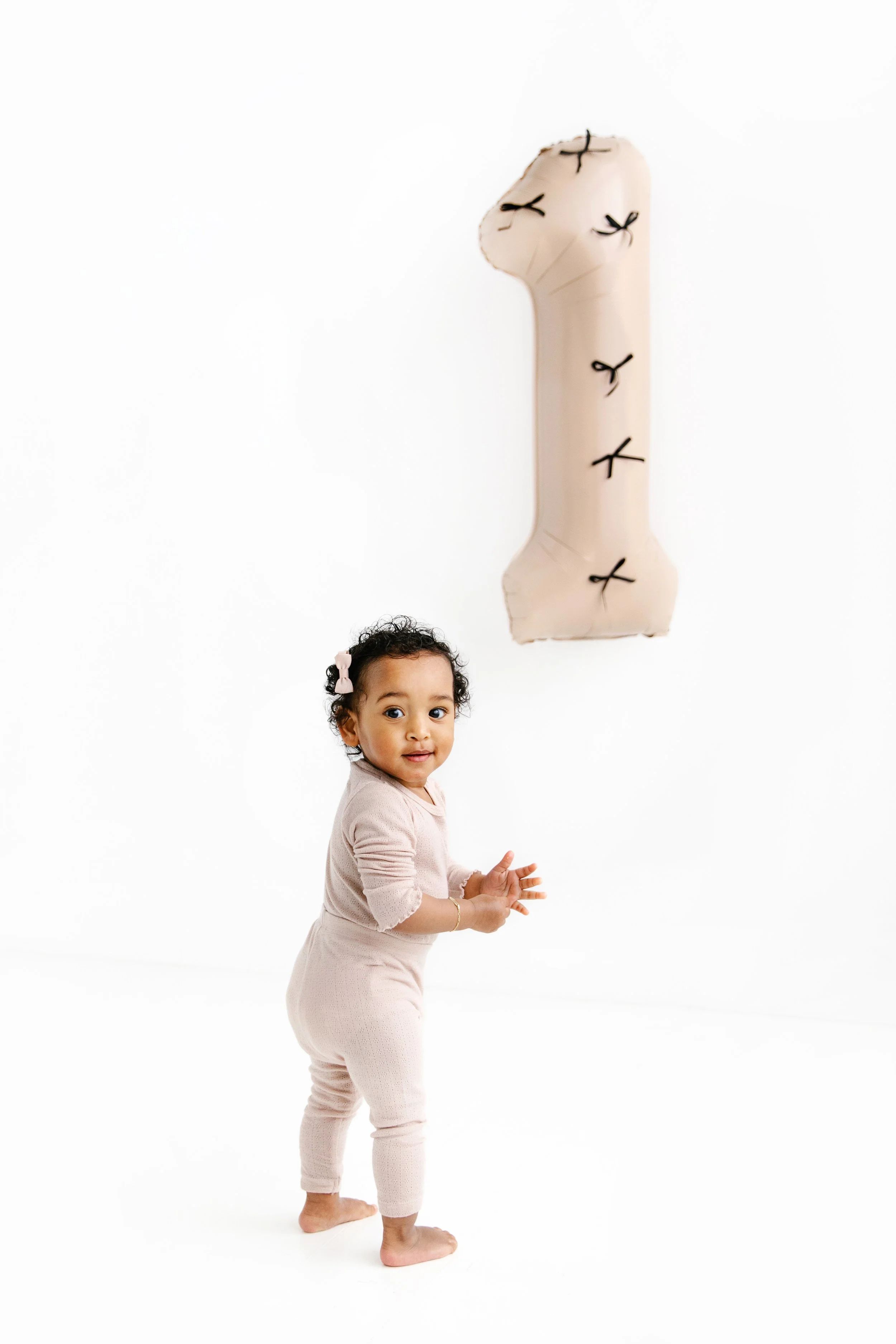 En ettåring som håller en beige stor heliumballong.