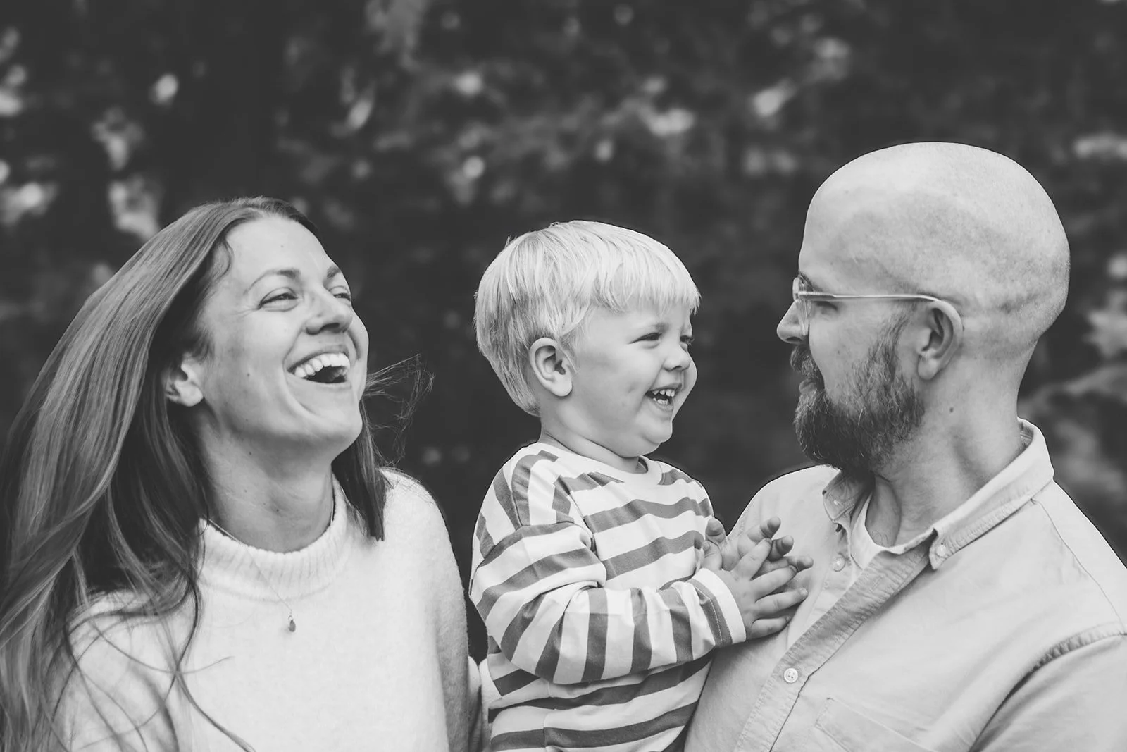En familj skrattar tillsammans under en utomhusfotografering.