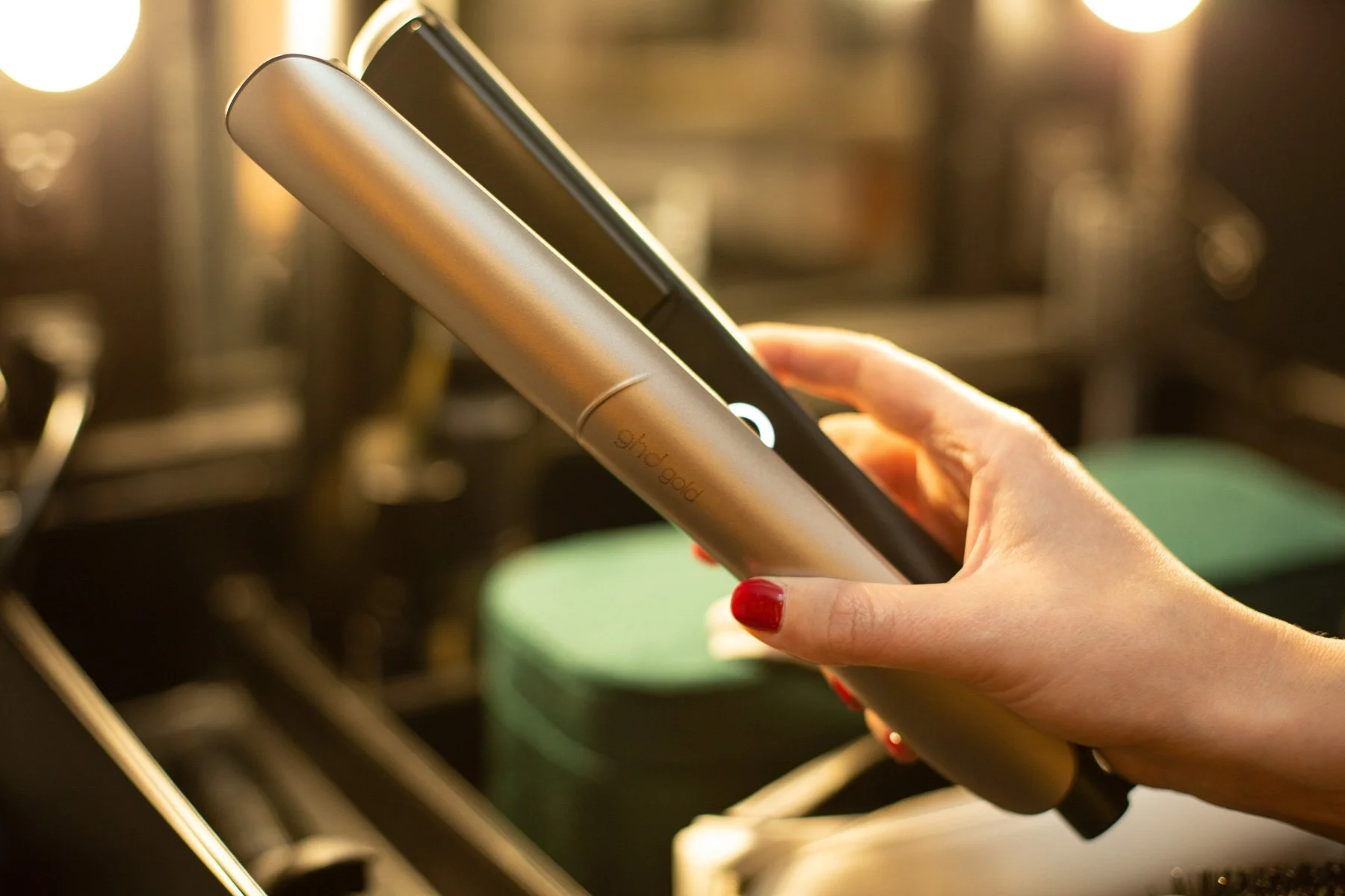 Commercial product photography of ghd Gold straighteners in hand