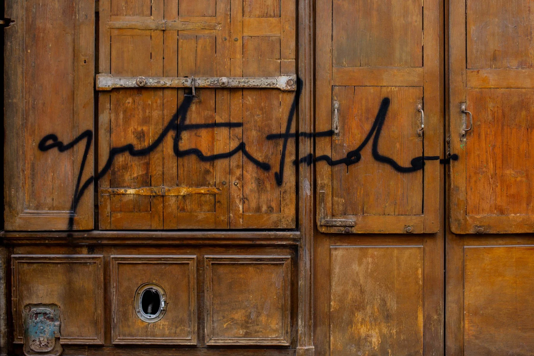 Graffiti painted on weathered wooden panel doors