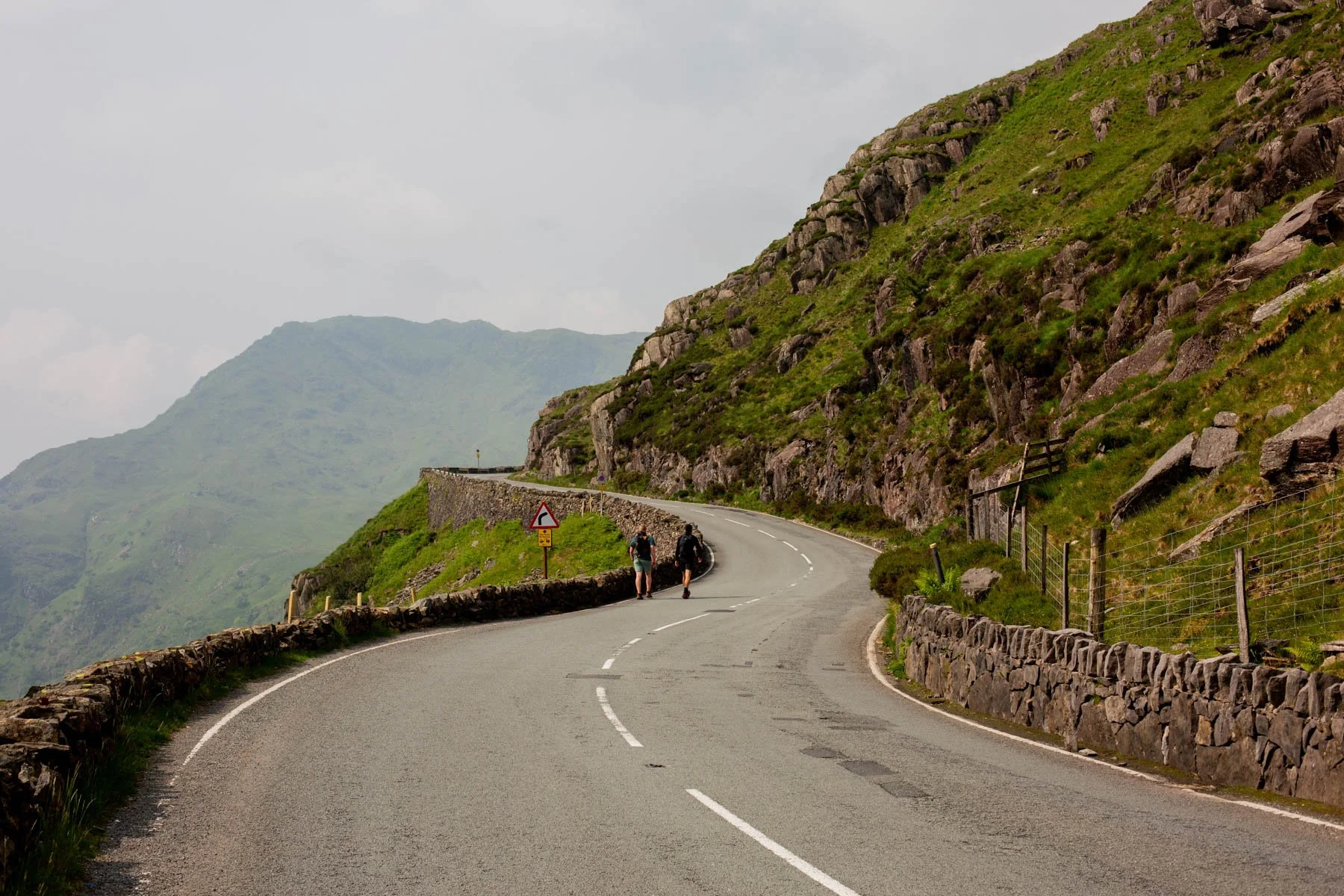 James and Austen walking along winding road in Snowdonia