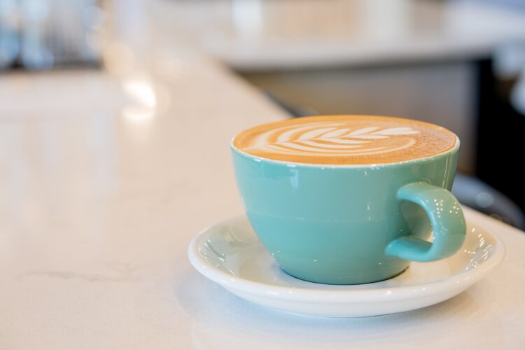 Latte in a light blue cup, sitting on a counter