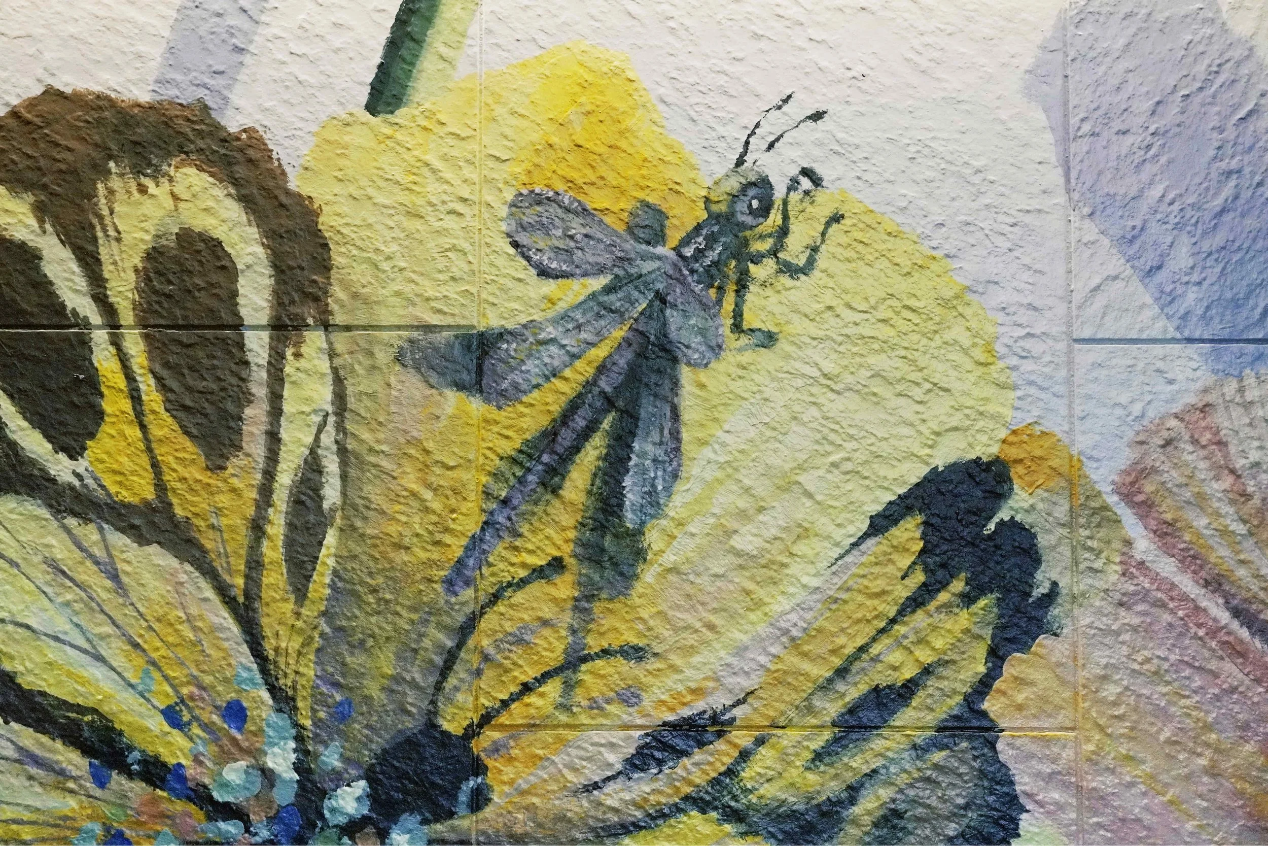 A mural created and painted by artist Neil Wang features a close-up of a purple dragonfly resting on a flower-like, whimsical yellow butterfly in Novoland Hong Kong by Sun Hung Kai Properties.