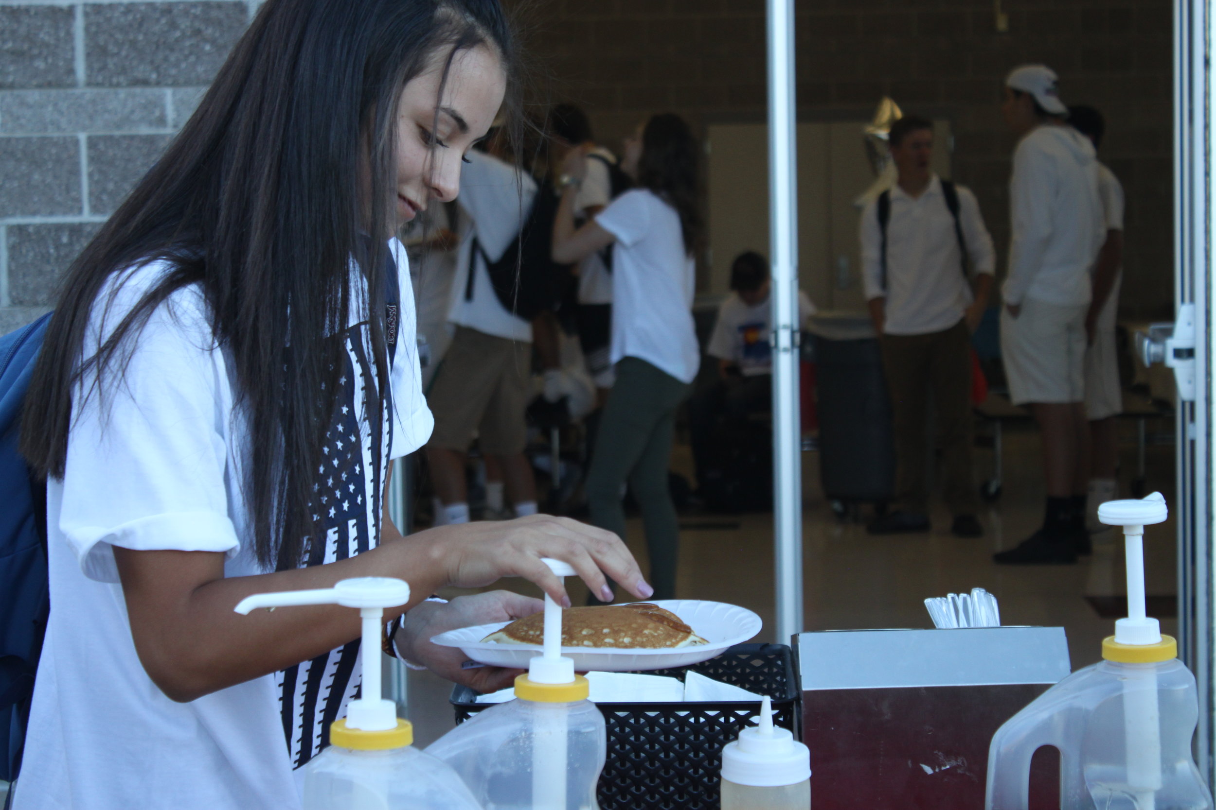  Senior Maisie Paulson puts syrup on her pancake at the annual FBLA and DECA breakfast.&nbsp; 