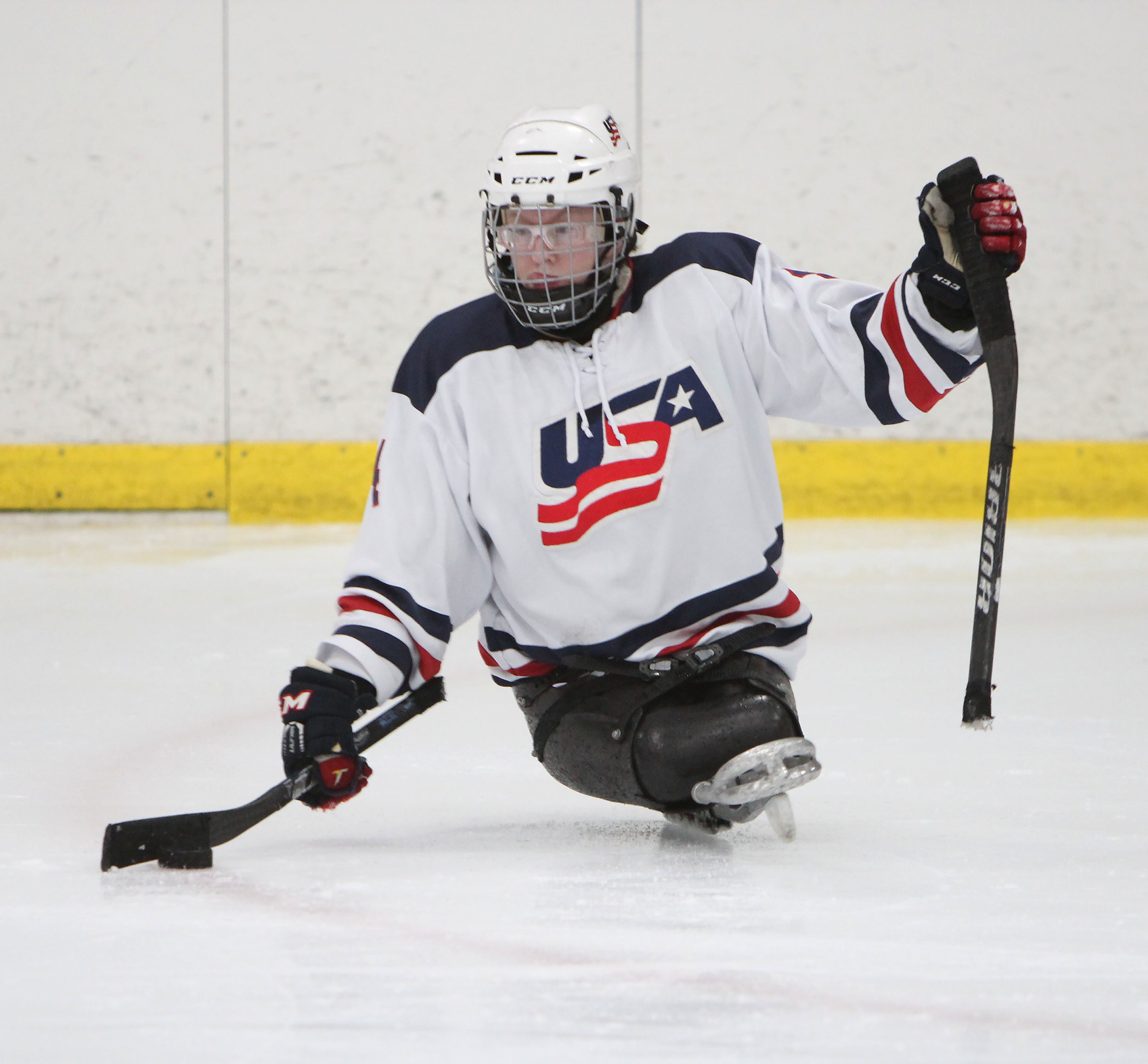 A U.S. Women's sled hockey forward grabs the puck before skating down towards the goal. 