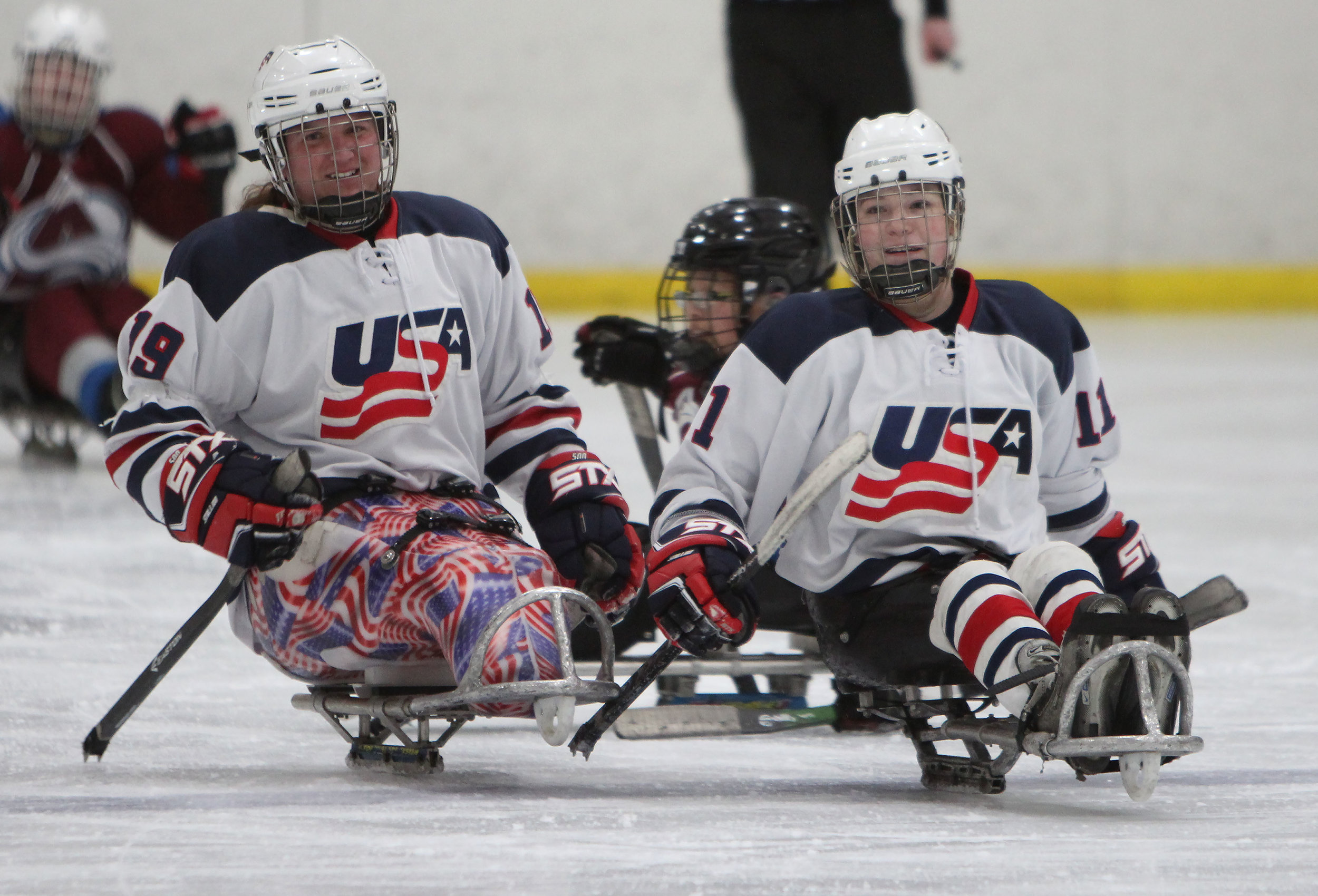 US Women's sled hockey teammates celebrate after a goal in a game against the Colorado Avalanche. 