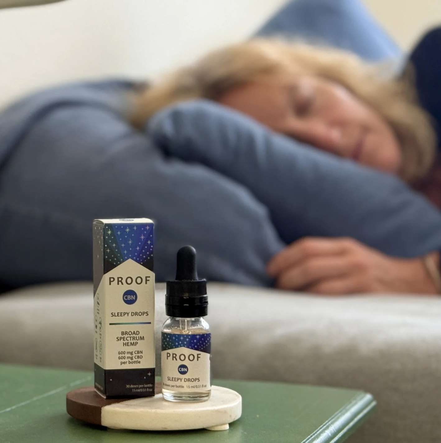 Proof Remedy CBD Sleepy Drops with woman sleeping in the background