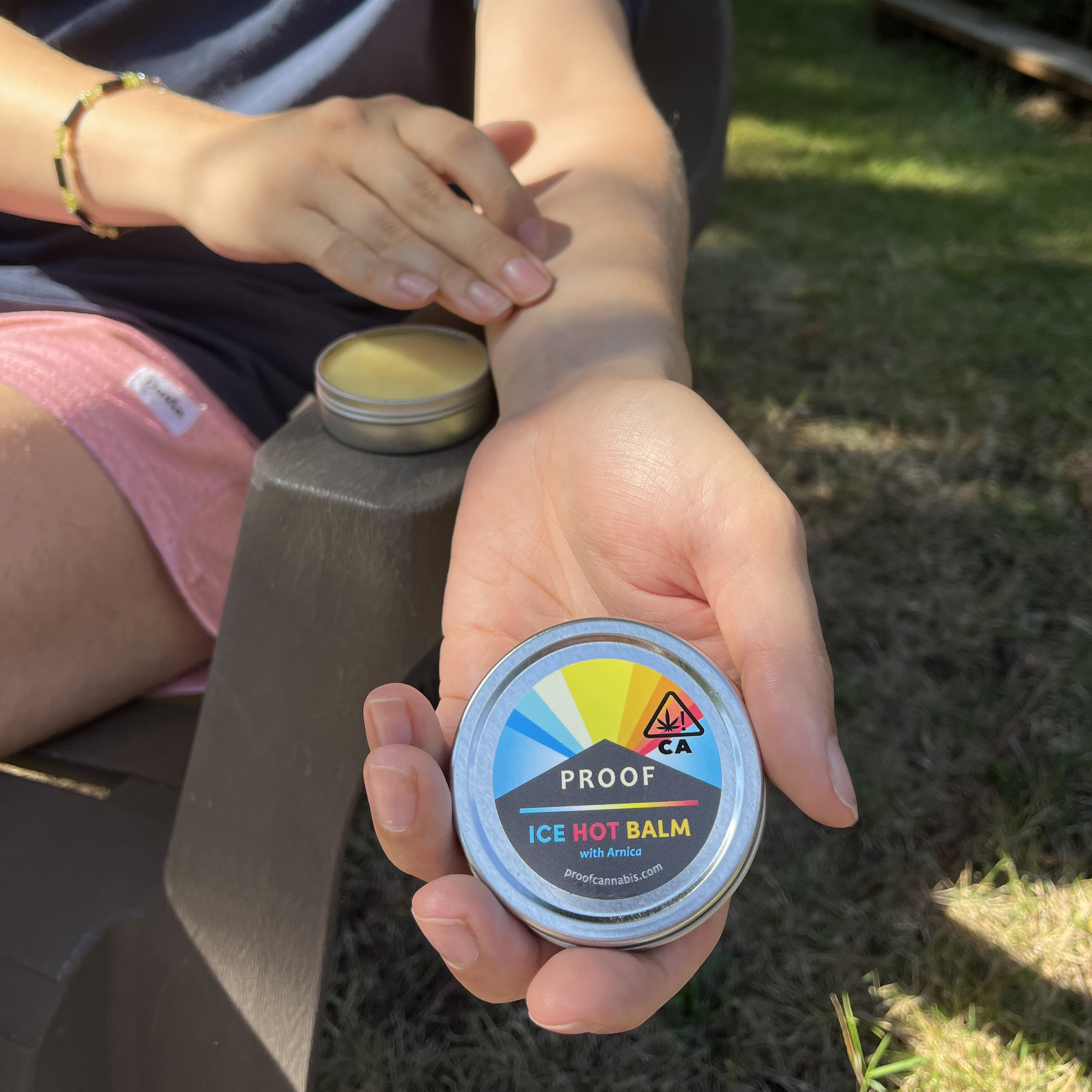 Person putting Proof Ice Hot Balm onto arm to relieve pain