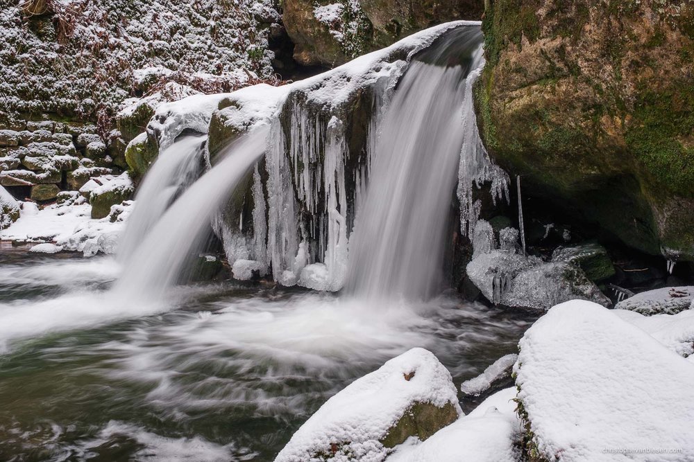 Visit the Mullerthal - Luxembourg - A cold winter has frozen parts of the Mullerthal's Schiessentumpel waterfall in northeastern Luxembourg - Frozen Waters
