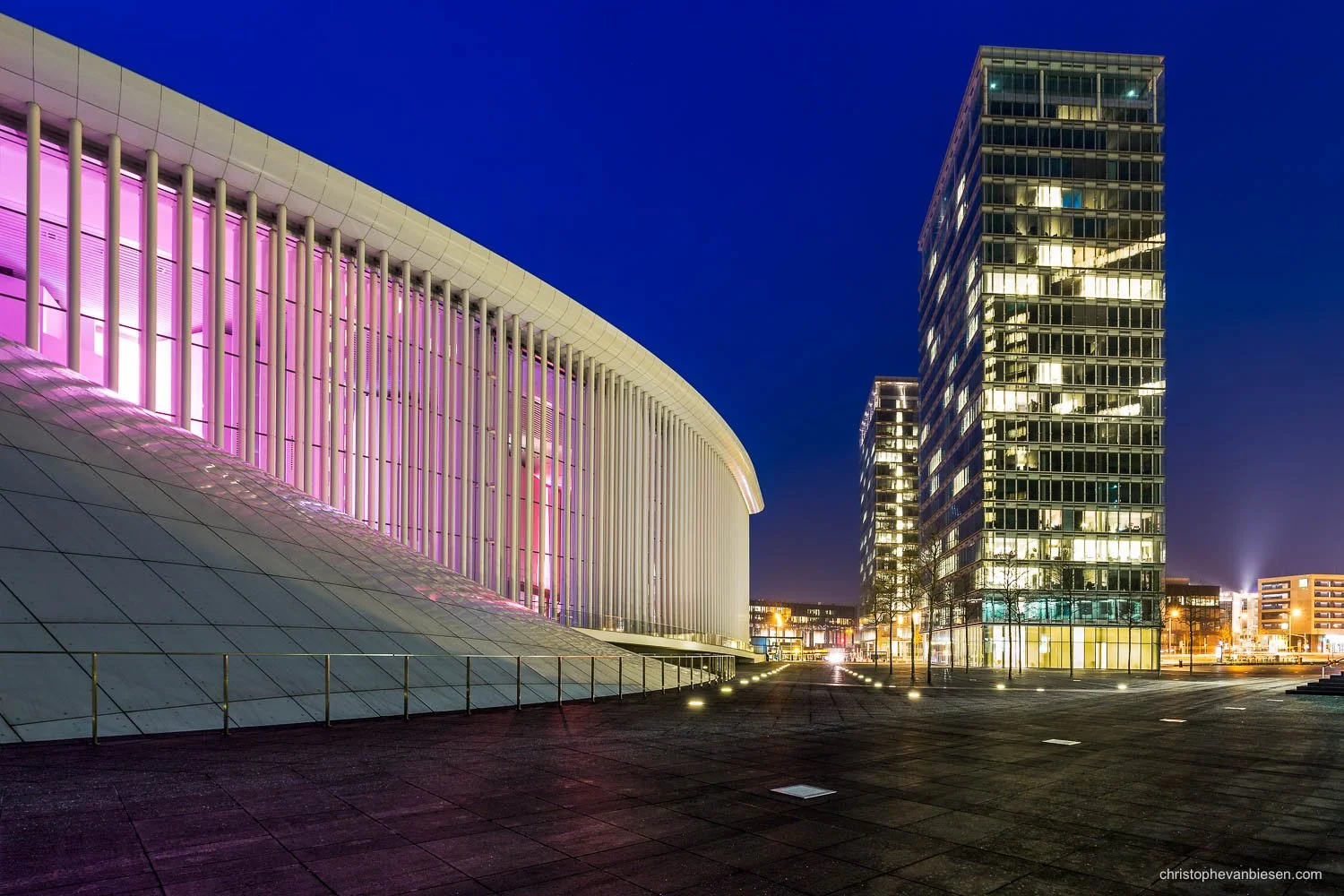 Luxembourg’s Philharmonie at night, with pink-lit white columns and illuminated office towers. |