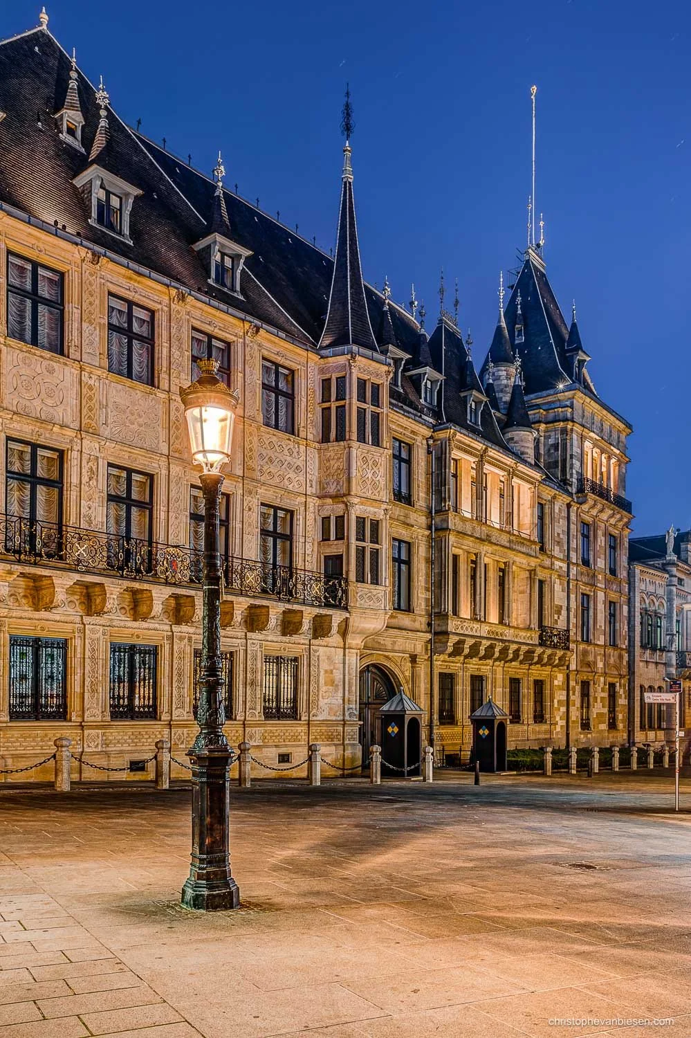 Grand Ducal Palace in Luxembourg City at night, with an illuminated façade and a street lamp in the foreground.