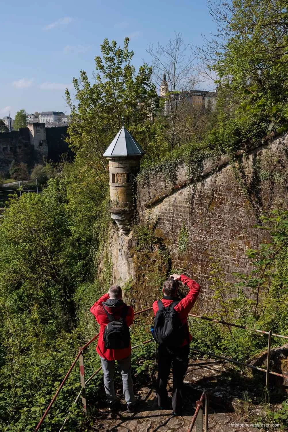 Two photographers beside the historic fortifications and a stone turret in Luxembourg City.