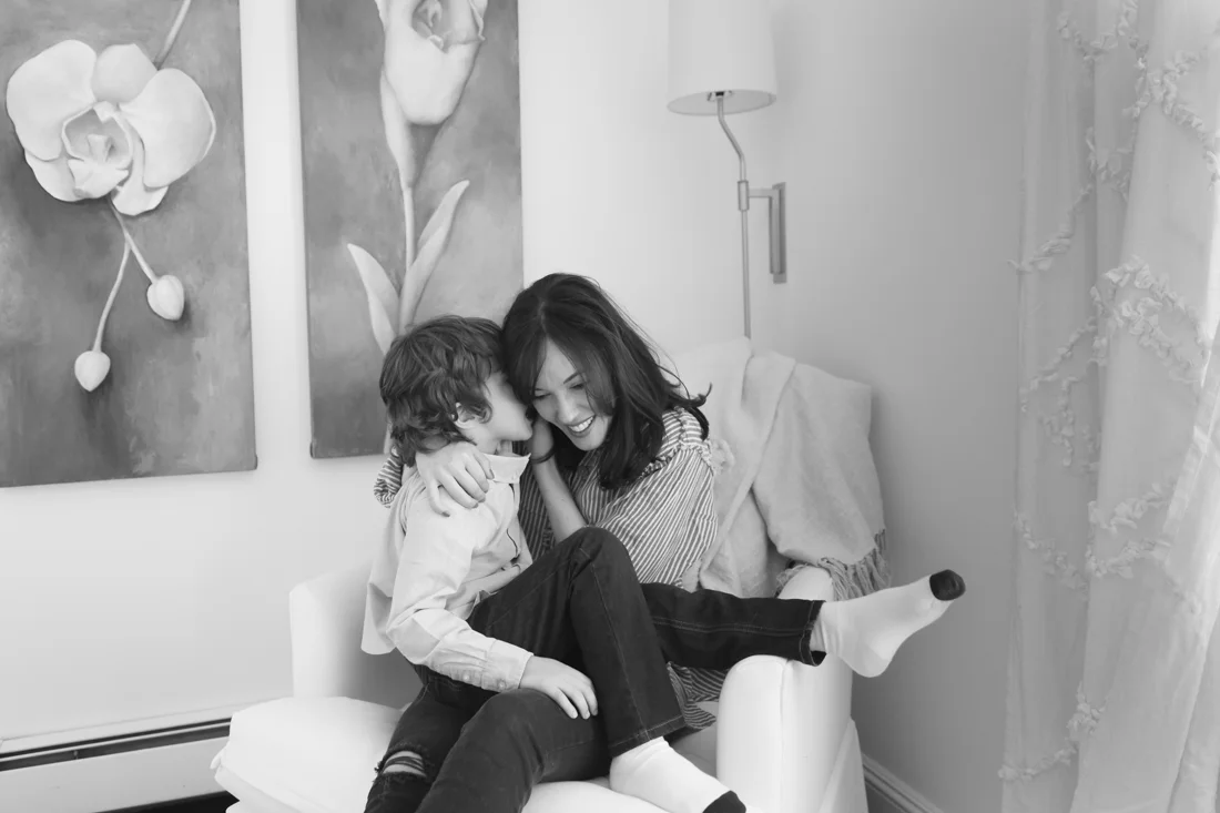 NYC FAMILY PHOTOgrapher - Mother hugging son on a corner chair in the bedroom