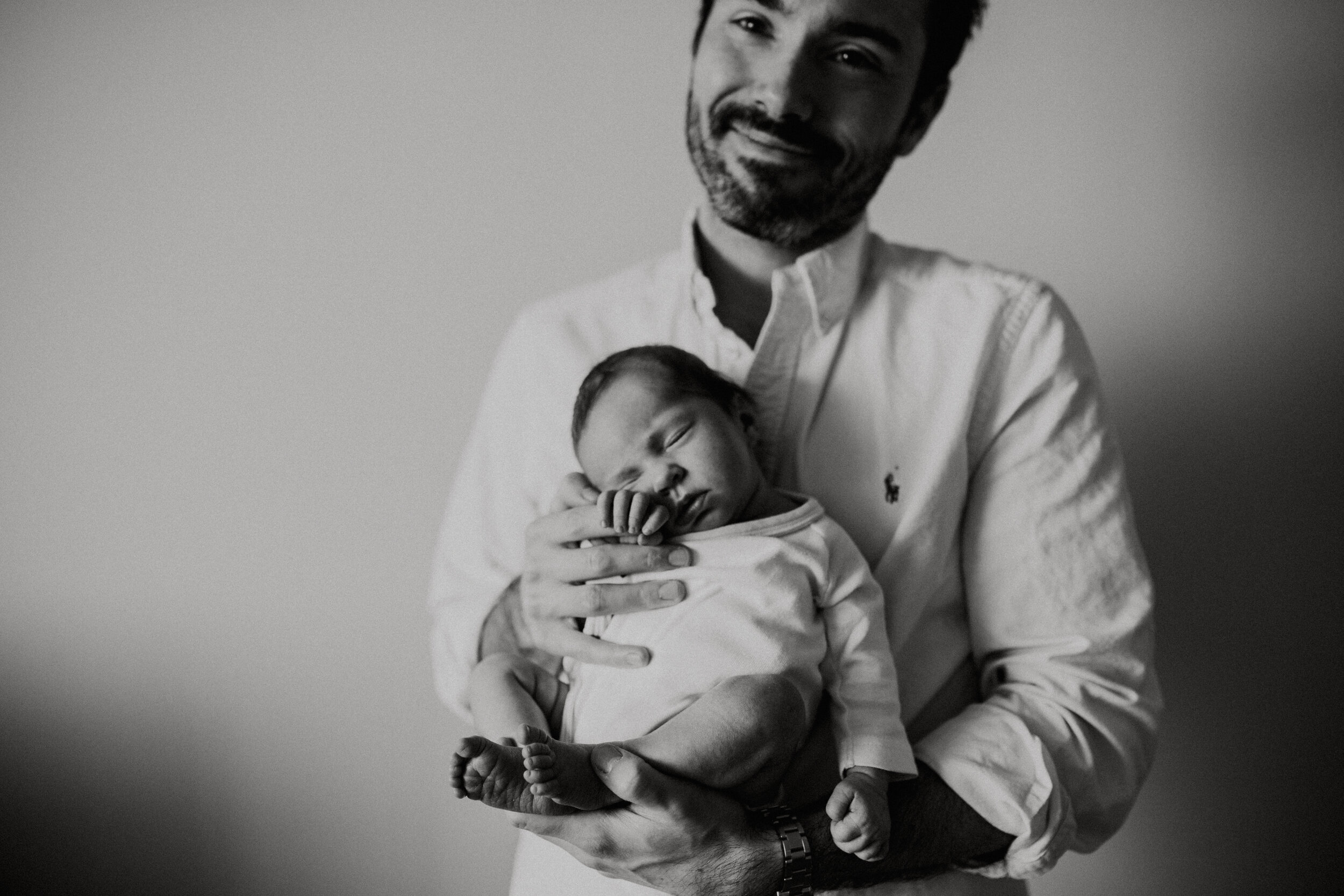 Dad holding his baby girl against his chest during an in home session with Paris Newborn Photographer Helene Djebiri