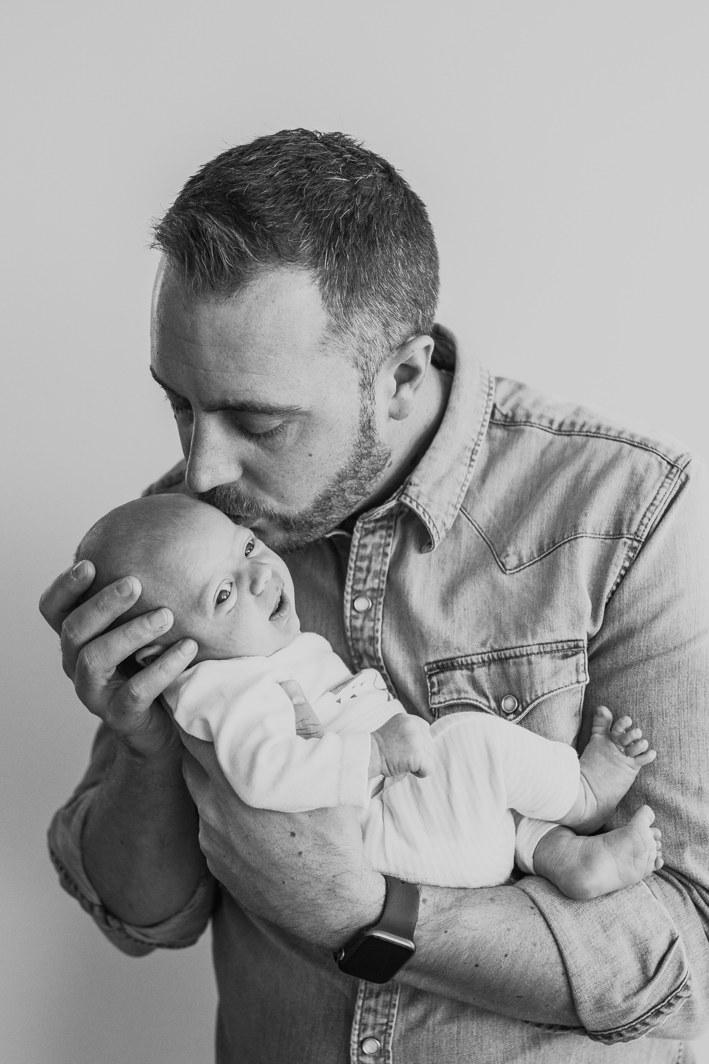 Dad kissing his baby boy during an in home session with Paris Newborn Photographer Helene Djebiri