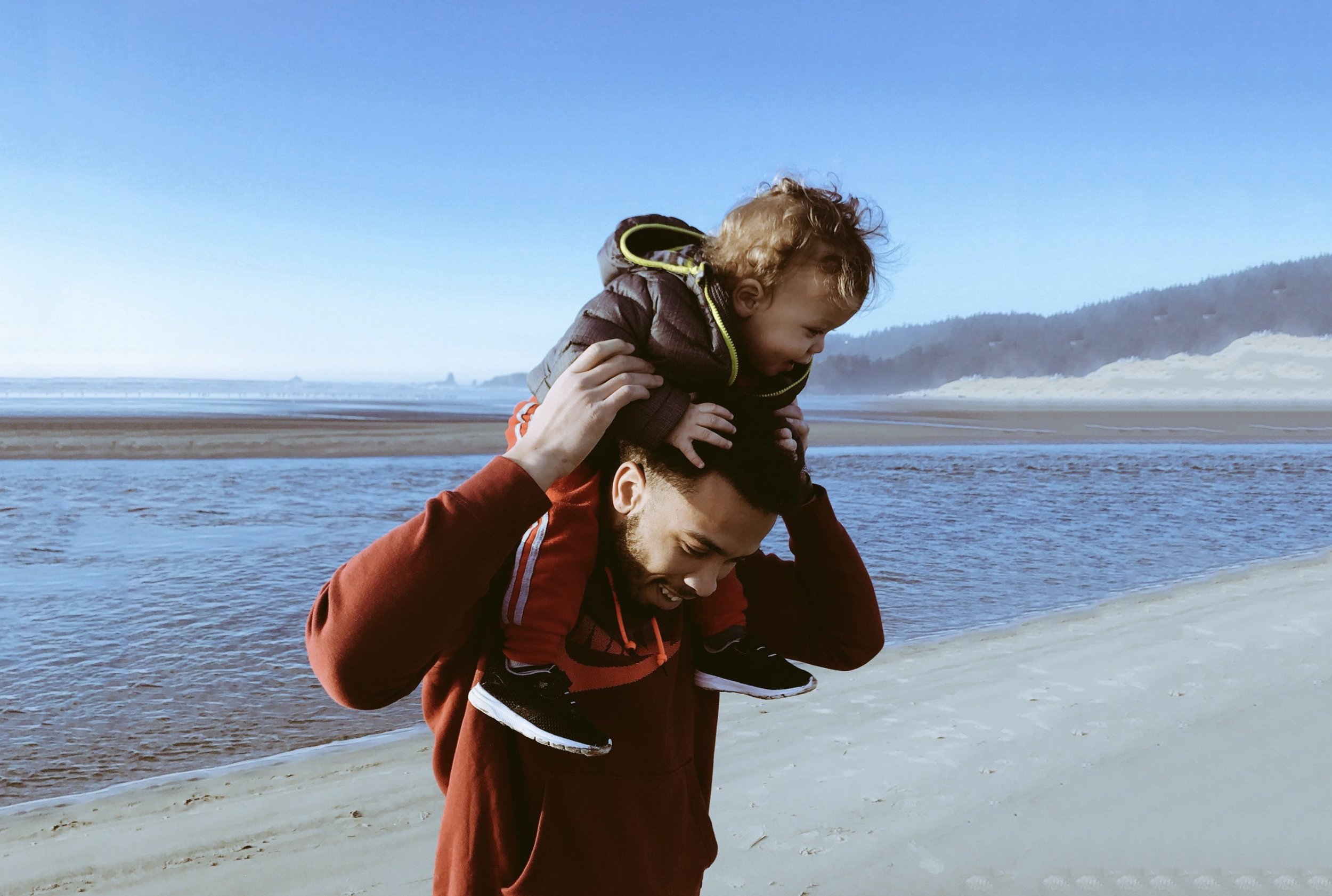 father with son on shoulders at beach.jpeg