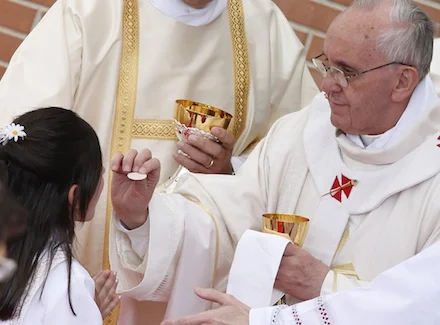 Pope Francis gives communion to a child. Photo source: catholicherald.co.uk