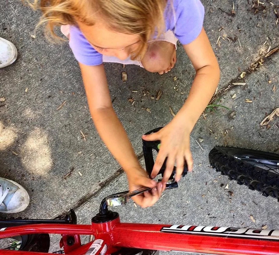 Young girls from Trips for Kids Charlotte works on her bike pedals.